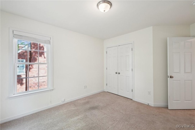 unfurnished bedroom with light colored carpet, baseboards, and a closet
