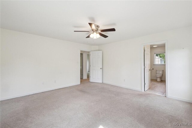 interior space featuring light colored carpet, baseboards, and a ceiling fan
