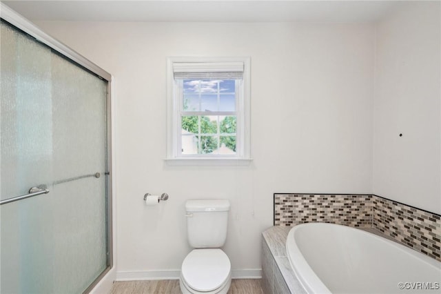 full bathroom with a bath, a shower stall, toilet, and baseboards