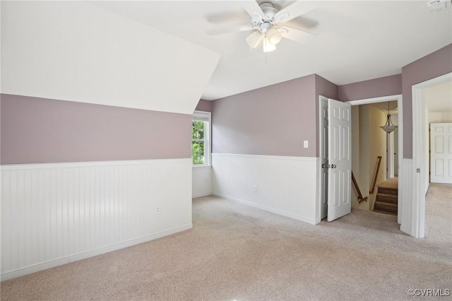 additional living space featuring carpet, ceiling fan, and wainscoting