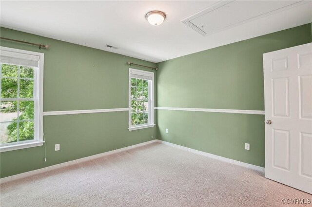 empty room featuring attic access, baseboards, carpet flooring, and visible vents