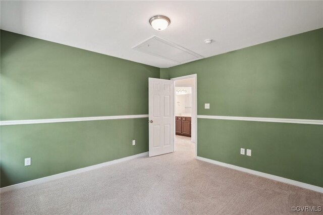 spare room featuring attic access, baseboards, and light colored carpet