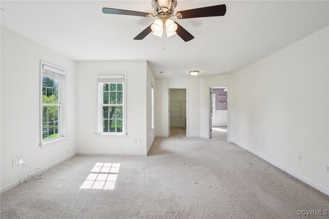 carpeted empty room with a ceiling fan and baseboards