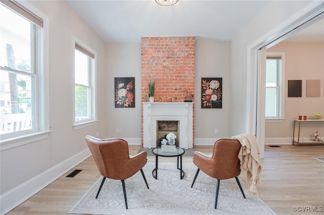 6 S Rowland St, Richmond, VA 23220 - living area with a brick fireplace, light wood-style flooring, visible vents, and a wealth of natural light