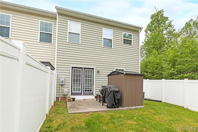 back of property with a patio area, an outdoor structure, a fenced backyard, a lawn, and a shed