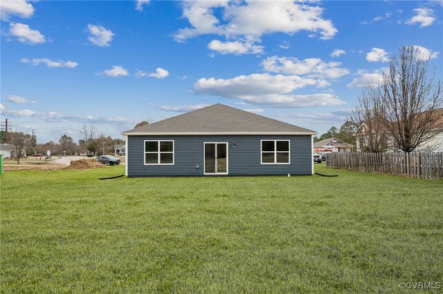 rear view of property with fence, a shingled roof, and a yard