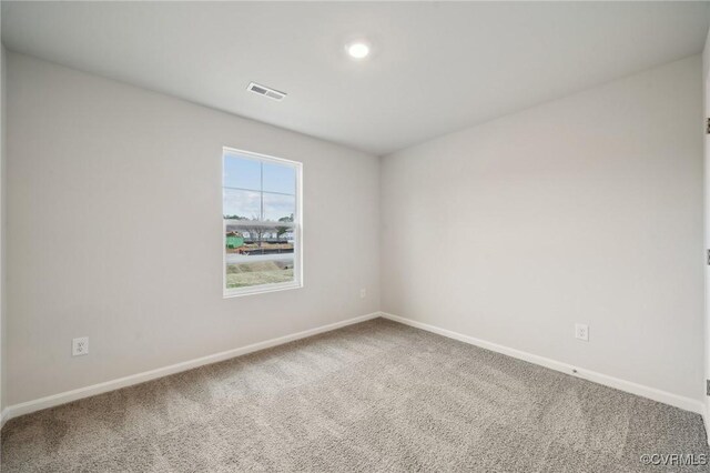 carpeted spare room featuring baseboards and visible vents