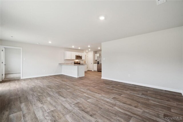 unfurnished living room featuring baseboards, wood finished floors, and recessed lighting