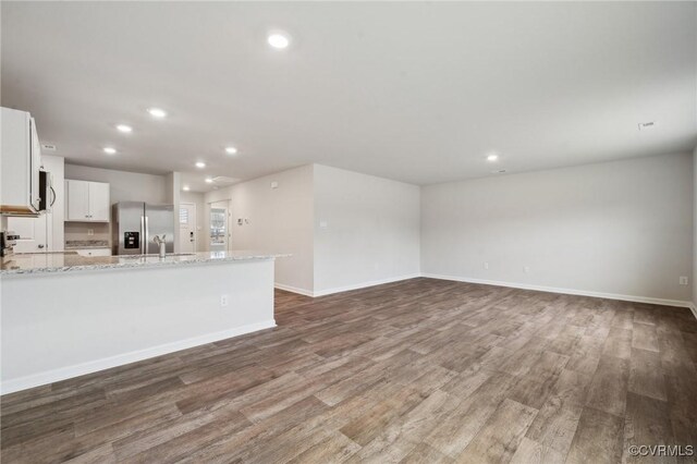 unfurnished living room featuring baseboards, wood finished floors, recessed lighting, and a sink