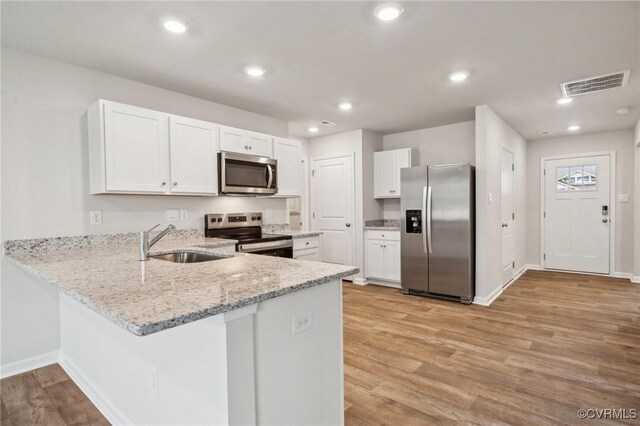 kitchen with a peninsula, a sink, baseboards, visible vents, and appliances with stainless steel finishes