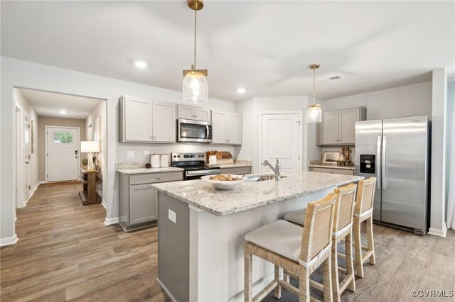 kitchen with a sink, decorative light fixtures, light wood-type flooring, gray cabinetry, and appliances with stainless steel finishes