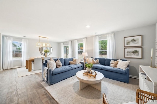 living room featuring a wealth of natural light, light wood finished floors, and an inviting chandelier