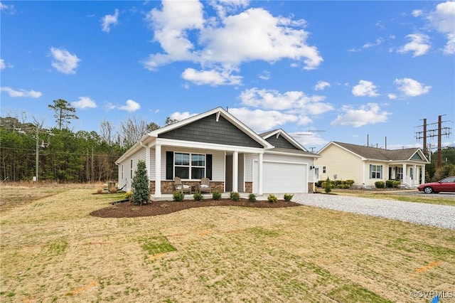 view of front facade featuring a garage, driveway, stone siding, a porch, and a front yard