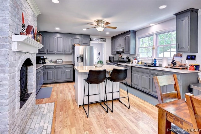 kitchen with stainless steel appliances, a ceiling fan, a sink, a center island, and gray cabinetry