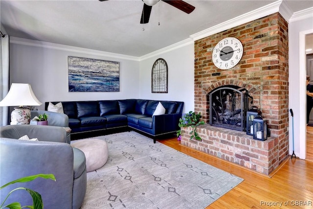 living area featuring ornamental molding, wood finished floors, a fireplace, and ceiling fan
