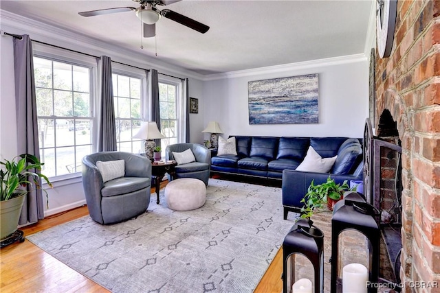 living area with crown molding, a ceiling fan, wood finished floors, and a fireplace