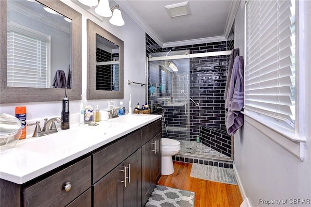 bathroom featuring crown molding, wood finished floors, a sink, and a stall shower
