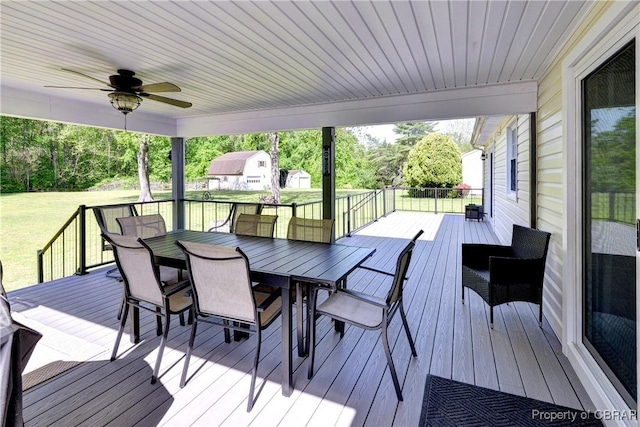 deck with outdoor dining area, a yard, and ceiling fan
