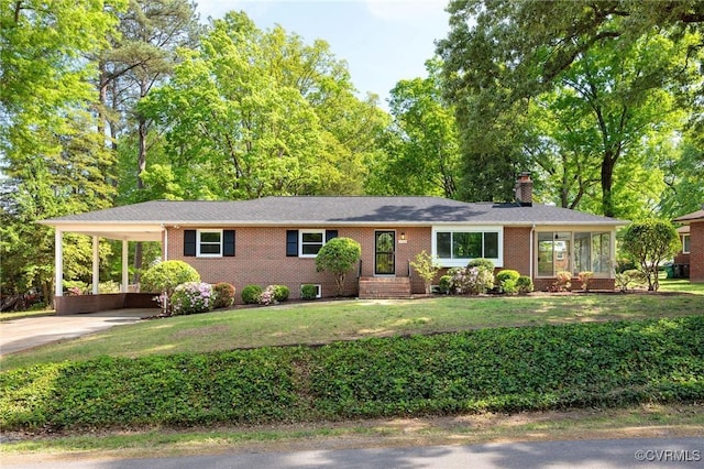 ranch-style house featuring a front lawn, an attached carport, a chimney, concrete driveway, and brick siding