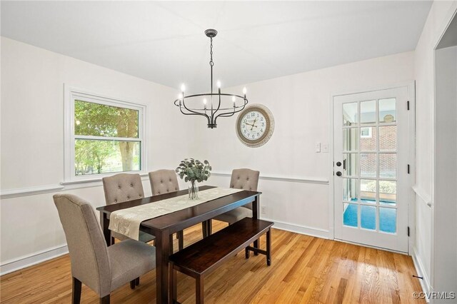 dining room featuring light wood-style flooring, baseboards, and an inviting chandelier