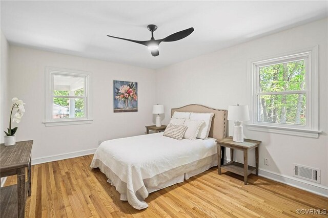 bedroom with baseboards, light wood-style flooring, visible vents, and multiple windows