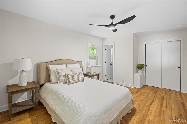 bedroom featuring light wood-type flooring, a ceiling fan, baseboards, and a closet