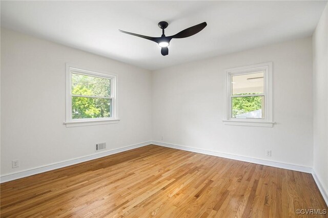 spare room with light wood-type flooring, baseboards, visible vents, and ceiling fan