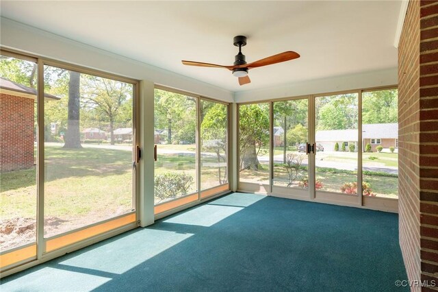 unfurnished sunroom featuring ceiling fan and a wealth of natural light