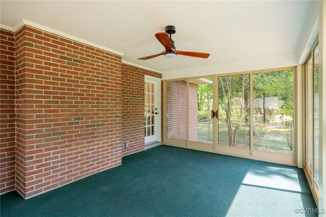 unfurnished sunroom featuring crown molding, carpet flooring, and brick wall