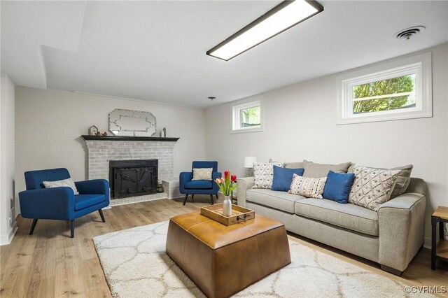 living room with light wood finished floors, visible vents, and a fireplace