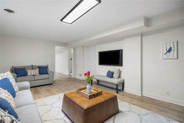 living area featuring baseboards, wood finished floors, and visible vents