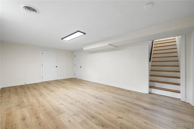 interior space with stairs, baseboards, visible vents, and light wood-style floors