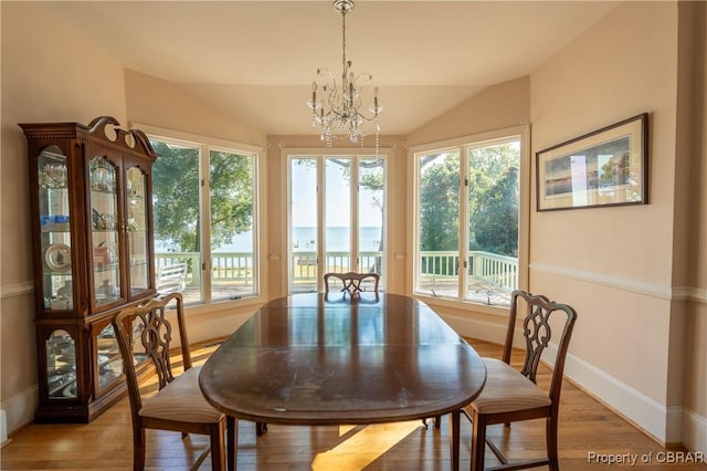 dining room with a chandelier, plenty of natural light, and lofted ceiling