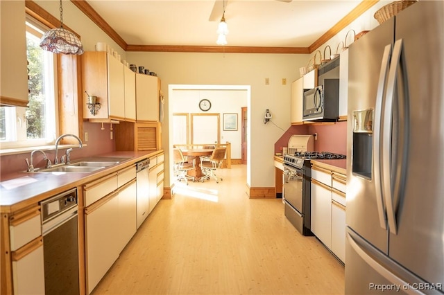 kitchen featuring crown molding, light wood-style floors, stainless steel appliances, and a sink