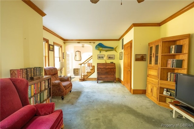 sitting room with stairway, ceiling fan, baseboards, ornamental molding, and carpet flooring