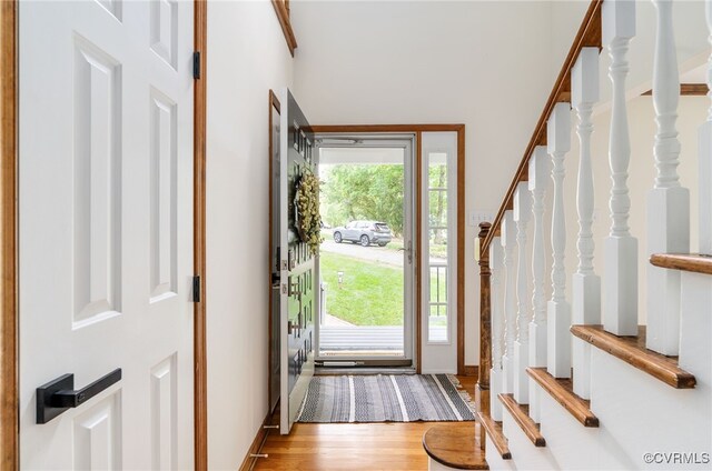 foyer entrance featuring stairway, light wood finished floors, and baseboards