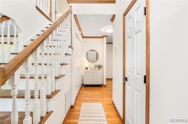 stairway featuring wood finished floors and ornamental molding