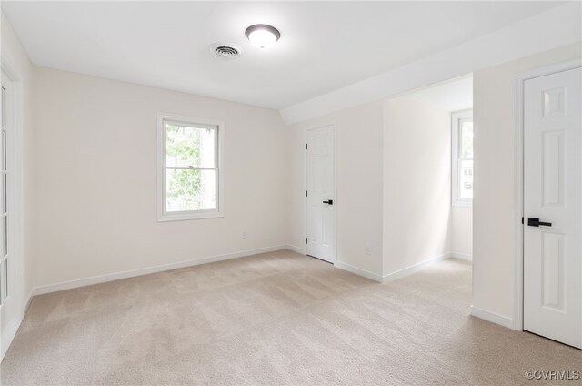 spare room with light colored carpet and baseboards