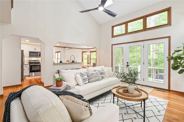living room featuring high vaulted ceiling, light wood-style floors, baseboards, and a ceiling fan