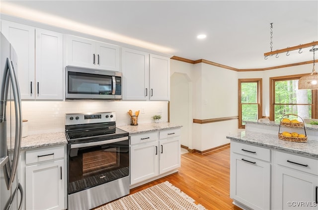kitchen featuring appliances with stainless steel finishes, decorative backsplash, white cabinets, light wood finished floors, and ornamental molding
