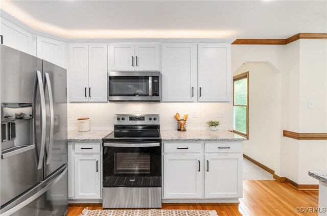 kitchen with appliances with stainless steel finishes, light wood-style floors, and tasteful backsplash