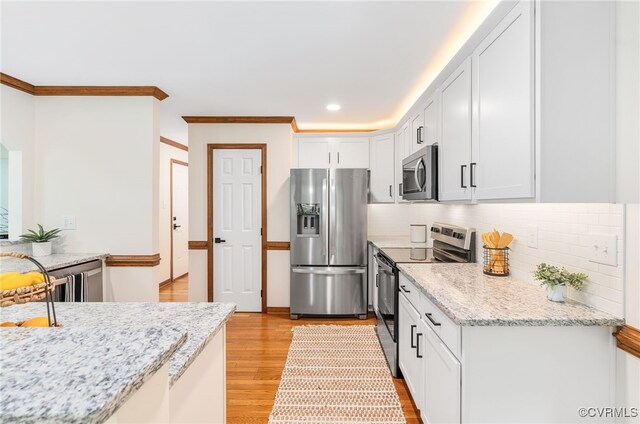kitchen featuring stainless steel appliances, backsplash, light wood-type flooring, white cabinets, and crown molding