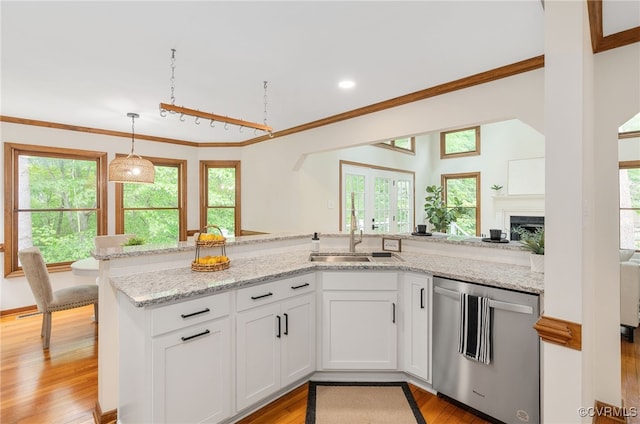 kitchen featuring dishwasher, a sink, ornamental molding, white cabinetry, and light wood-style flooring