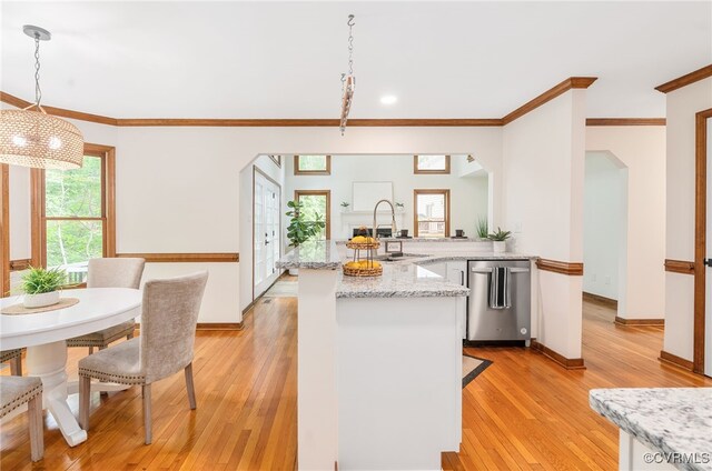 kitchen featuring a sink, arched walkways, a peninsula, dishwasher, and crown molding