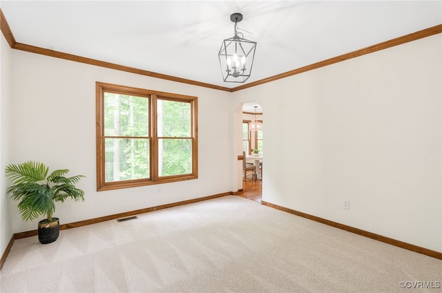carpeted spare room with arched walkways, baseboards, ornamental molding, and a chandelier