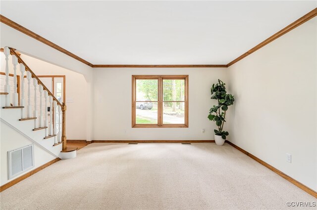 spare room featuring baseboards, ornamental molding, light colored carpet, and stairway