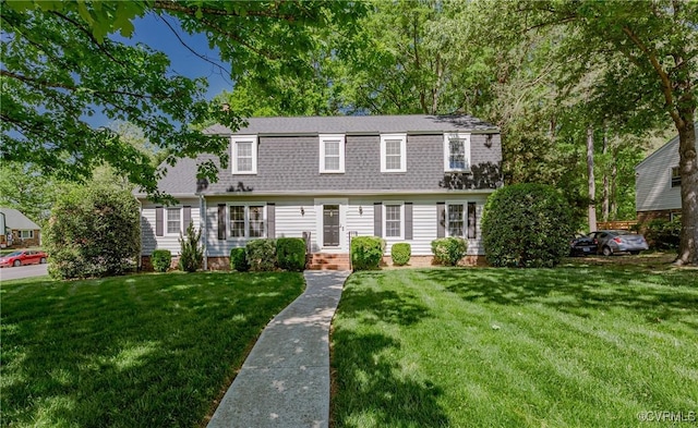 view of front of house featuring a gambrel roof, a front yard, and a shingled roof