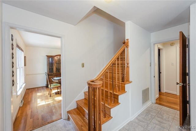 staircase featuring baseboards and visible vents