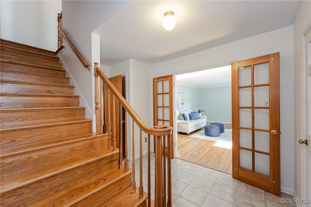 stairway with baseboards, ornamental molding, french doors, and tile patterned flooring