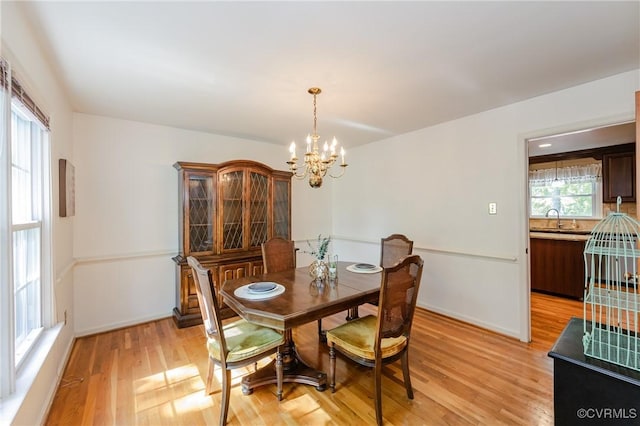 dining room with light wood-style floors, baseboards, and a notable chandelier